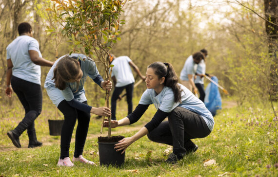 Mother and daughter preparing to plant a tree in the woods, volunteering to help with nature conservation and reforestation. Activists offering service to fight for environmental protection.